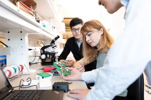 Students holding and looking at an engineering device