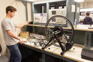 A young man working on a bicycle wheel and parts on a table