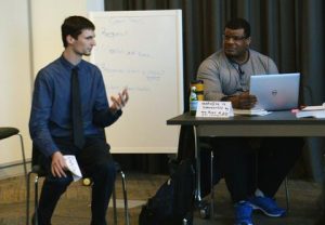 Two young men sitting next to each other, talking