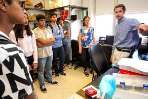 students standing in a lab, listening to an instructor