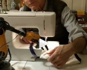 man sewing a mask with help from a robotic device