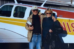 Two people standing in front of an airplane