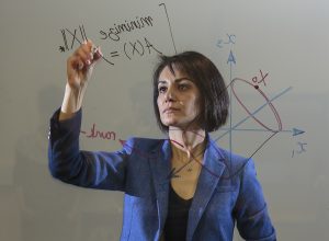 Maryam Fazel writing equations on a glass wall