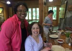 Three women smiling at a buffet table.