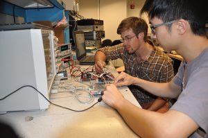 Two young men working on an electronic device