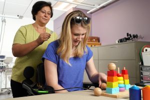 female researcher applies spinal stimulation pads to the back of study participant's neck