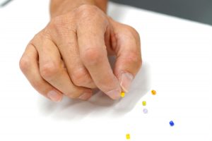 photo of hand picking up a small bead