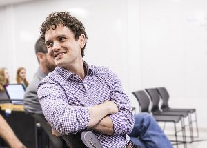 Sam Burden sitting and smiling in a meeting