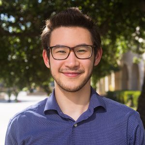 Headshot of man in glasses and wearing a blue button up shirt