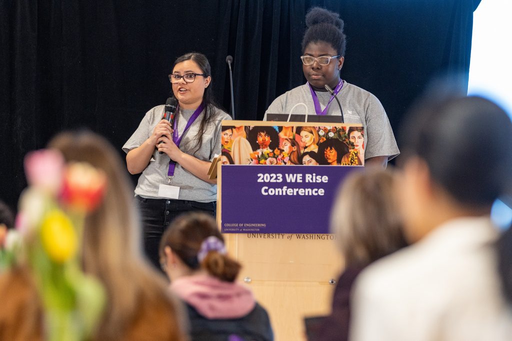 We Rise podium and two female speakers