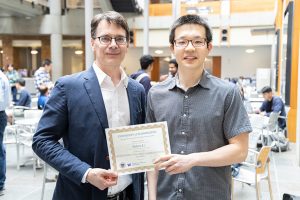 UW ECE Professor Eric Klavins standing next to Outstanding Teaching Assistant Award recipient Xichen Li. The two are holding Li's award certificate.