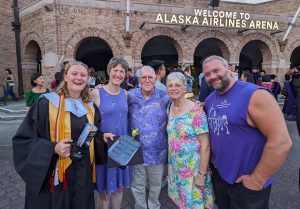 Margot Adam in Graduation cap and gown, with her parents and grandparents outside the Hec-Edmundson Pavilion on the UW campus