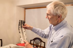 Gary Bernard holding two sheets of thin, clear plastic film, which are covered with black dots