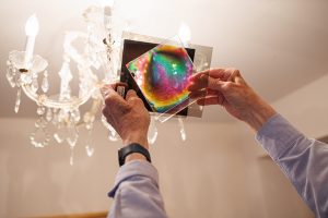 Hands holding rainbow-colored plastic sheets up to a light