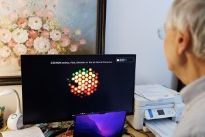 Looking over Bernard's shoulder at a black computer screen that contains a colorful image of the hexagonal lenses that make up a butterfly's compound eye