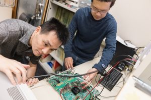 Two men working on a motherboard covered with circuits