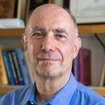 UW ECE Professor Daniel Kirschen stands in front of a wall of books in his office.