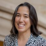 Professor Kai-Mei Fu standing in front of a stone staircase in the UW Suzzallo Library.