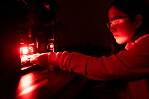 Mary Bun in the red light of the rig she made to study multitasking in fruit flies.