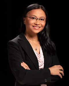 Portrait photo of Thy Tran smiling with her arms crossed in front of her chest.