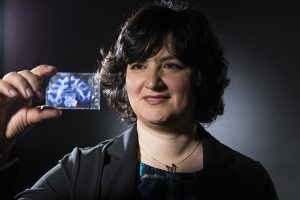UW ECE and BioE Associate Professor Azadeh Yazdan holds up a slide containing a thin section of a brain