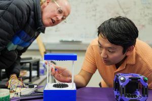 UW ECE and Allen School Professor Josh Smith observes Jared Nakahara work with levitated droplets in their tabletop acoustic levitation prototype.