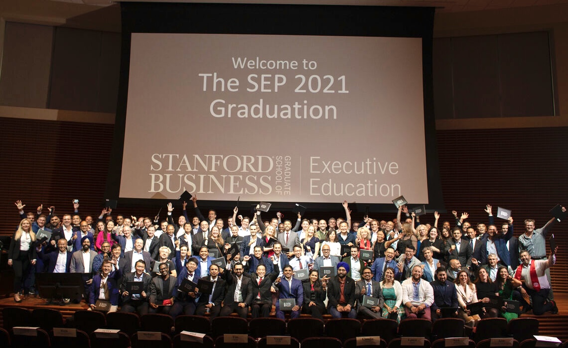 Tran stands with the Stanford Graduate School of Business Executive Program 2021 cohort afterdelivering the commencement address as the featured graduation speaker.