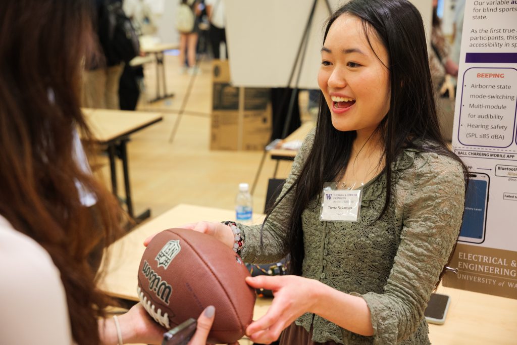 Student at ENGINE capstone event holding enhanced football for blind players